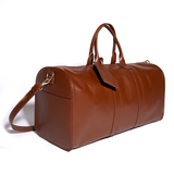 Cardela brown leather weekend bag with side pockets, shoulder strap, and interior lining on a white background